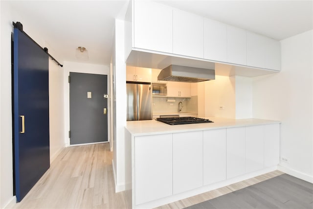 152-18 Union Tpke Unit 12T, Flushing, NY 11367 - kitchen featuring appliances with stainless steel finishes, extractor fan, a barn door, light wood finished floors, and backsplash