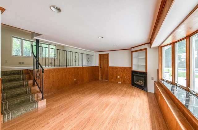 3 N Jackson Rd, Poughkeepsie, NY 12603 - unfurnished living room featuring a wainscoted wall, a fireplace, light wood-style flooring, crown molding, and wood walls