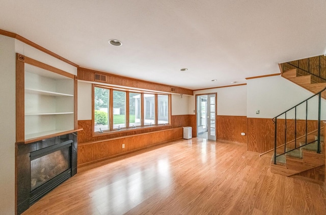 3 N Jackson Rd, Poughkeepsie, NY 12603 - unfurnished living room with wainscoting, crown molding, wood walls, a glass covered fireplace, and wood finished floors
