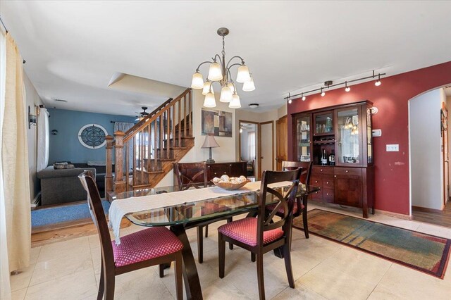 8 Pearl St, Bethpage, NY 11714 - dining space featuring rail lighting, arched walkways, stairs, a chandelier, and ceiling fan