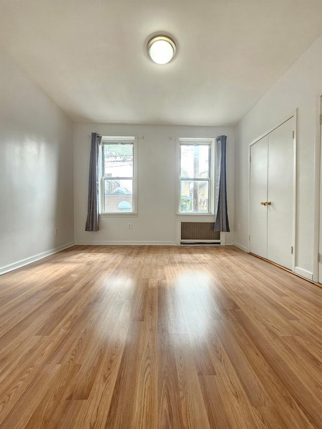 1714 W 12th St, Brooklyn, NY 11223 - empty room featuring radiator heating unit, healthy amount of natural light, and light wood finished floors