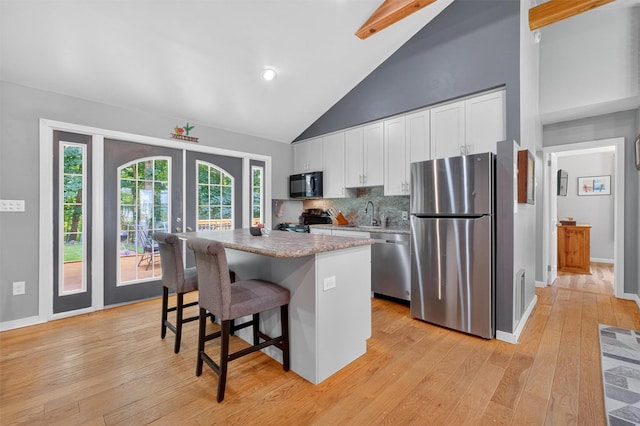 69 Floradan Rd, Putnam Valley, NY 10579 - kitchen featuring stainless steel appliances, white cabinets, a kitchen bar, a kitchen island, and light wood-style floors