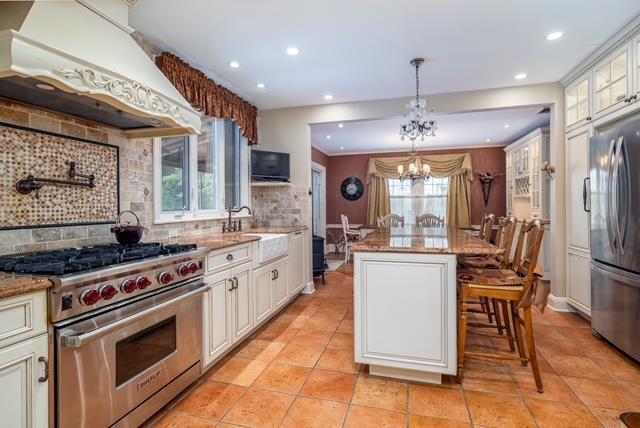 11 Loel Ct, Rockville Centre, NY 11570 - kitchen featuring appliances with stainless steel finishes, custom range hood, recessed lighting, tasteful backsplash, and glass insert cabinets