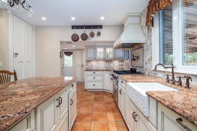 11 Loel Ct, Rockville Centre, NY 11570 - kitchen with backsplash, high end stainless steel range oven, premium range hood, glass insert cabinets, and light stone countertops