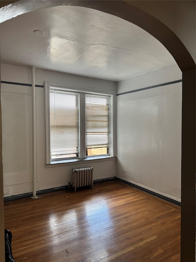2922 Barnes Ave Unit 3A, Bronx, NY 10467 - empty room featuring radiator heating unit, arched walkways, and wood finished floors