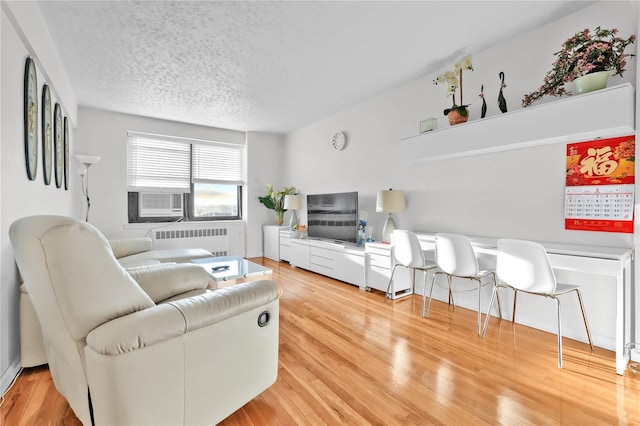 139-09 28th Rd Unit 6F, Flushing, NY 11354 - living room featuring radiator heating unit, light wood finished floors, a textured ceiling, and cooling unit