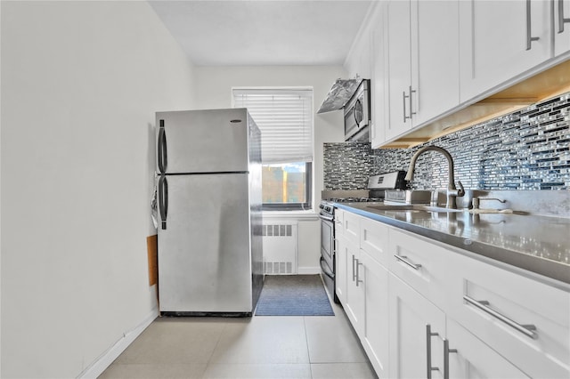 139-09 28th Rd Unit 6F, Flushing, NY 11354 - kitchen with stainless steel appliances, radiator, decorative backsplash, white cabinetry, and light tile patterned floors
