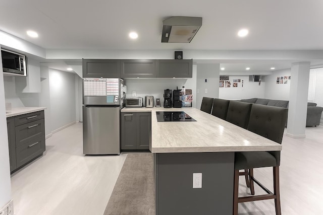 61 Ulster Ave, West Babylon, NY 11704 - kitchen with stainless steel appliances, a peninsula, a kitchen bar, light countertops, and light wood finished floors
