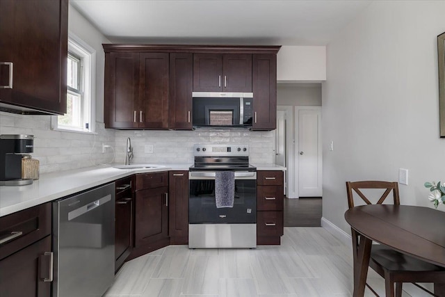 22324 Murdock Ave, Queens Village, NY 11429 - kitchen with stainless steel appliances, light countertops, decorative backsplash, and dark brown cabinetry