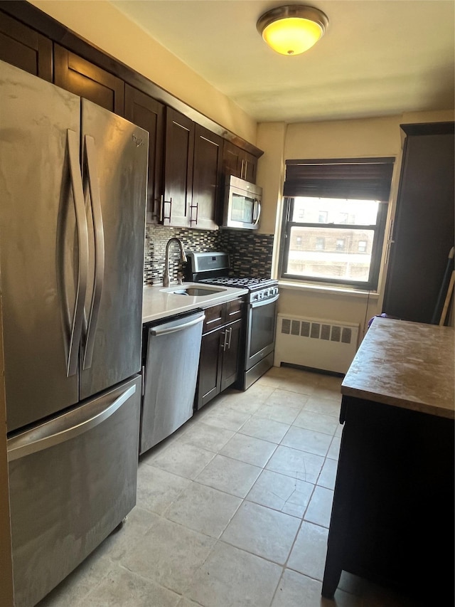 90-32 153rd Ave Unit 0029, Howard Beach, NY 11414 - kitchen featuring appliances with stainless steel finishes, radiator, backsplash, dark brown cabinets, and light tile patterned floors