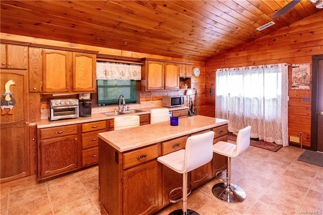 9 Low Rd, Wallkill, NY 12589 - kitchen with stainless steel microwave, vaulted ceiling, wooden walls, light countertops, and brown cabinets