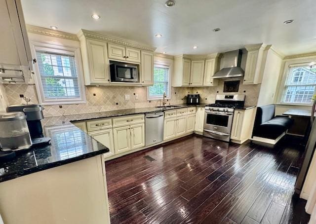 987 E Prospect St, Woodmere, NY 11598 - kitchen featuring wall chimney range hood, appliances with stainless steel finishes, cream cabinets, crown molding, and recessed lighting