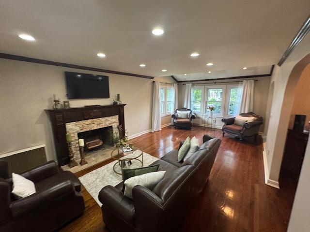 987 E Prospect St, Woodmere, NY 11598 - living room with arched walkways, wood finished floors, a stone fireplace, crown molding, and recessed lighting