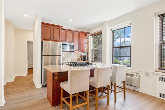 819 Broadway Unit 1G, Woodmere, NY 11598 - kitchen featuring stainless steel appliances, radiator heating unit, light wood-style floors, tasteful backsplash, and light stone countertops