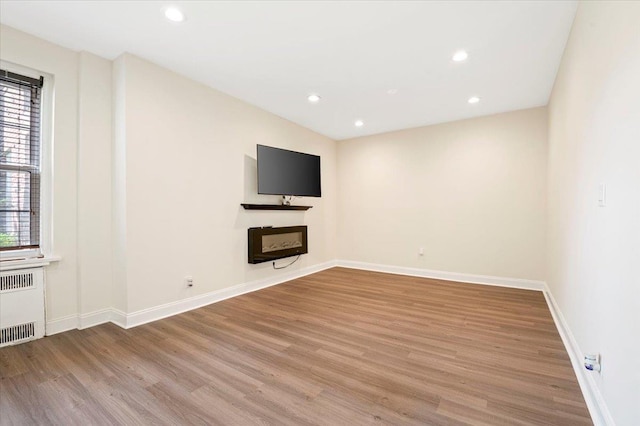 819 Broadway Unit 1G, Woodmere, NY 11598 - unfurnished living room with radiator, light wood finished floors, recessed lighting, and a fireplace