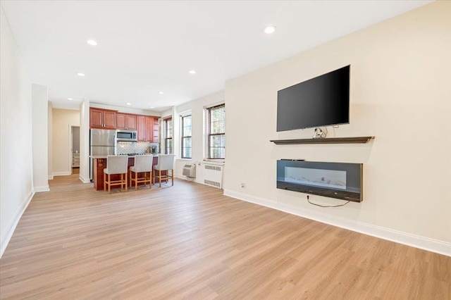 819 Broadway Unit 1G, Woodmere, NY 11598 - living room with light wood-style flooring, a glass covered fireplace, recessed lighting, and radiator