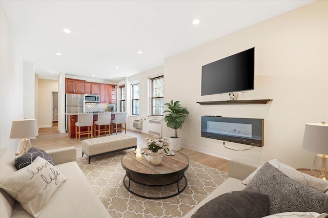 819 Broadway Unit 1G, Woodmere, NY 11598 - living room featuring light wood finished floors, a glass covered fireplace, recessed lighting, and radiator