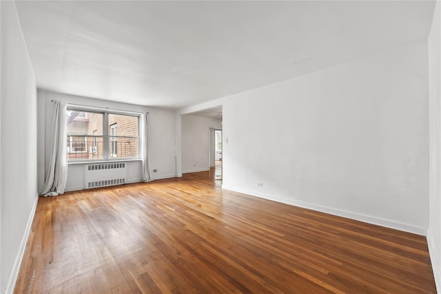 147-25 38th Ave Unit F26, Flushing, NY 11354 - empty room featuring radiator heating unit, plenty of natural light, and wood finished floors
