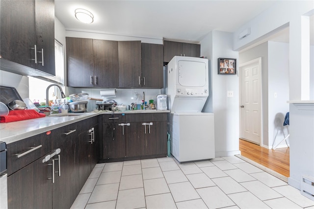 1051 Bay 32nd St, Bayswater, NY 11691 - kitchen with stacked washer and clothes dryer, light countertops, dark brown cabinetry, and light tile patterned floors