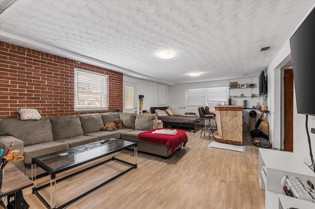 227 Randall Ave, Lawrence, NY 11559 - living area featuring brick wall, light wood-style flooring, and a textured ceiling