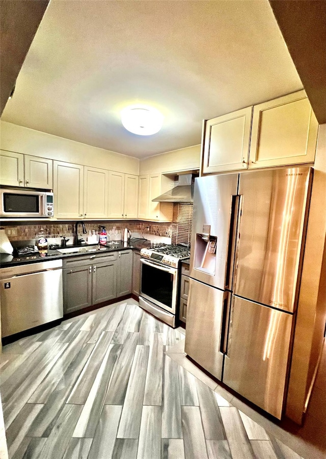 21019 26th Avenue Tl, Bayside, NY 11360 - kitchen with appliances with stainless steel finishes, wall chimney exhaust hood, dark countertops, decorative backsplash, and light wood-style floors