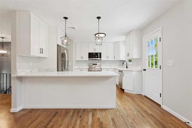 297 Farm To Market Rd, Brewster, NY 10509 - kitchen featuring stainless steel appliances, light wood-style flooring, a peninsula, and white cabinets