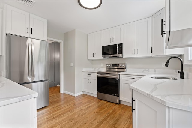 297 Farm To Market Rd, Brewster, NY 10509 - kitchen featuring appliances with stainless steel finishes, white cabinets, light wood finished floors, and light stone counters