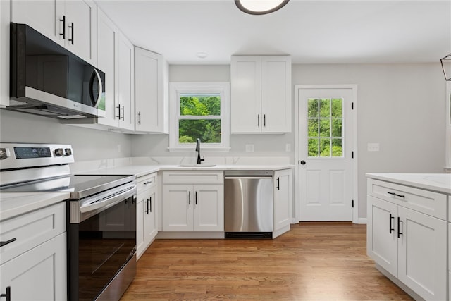 297 Farm To Market Rd, Brewster, NY 10509 - kitchen with stainless steel appliances, healthy amount of natural light, white cabinetry, and light wood-style floors