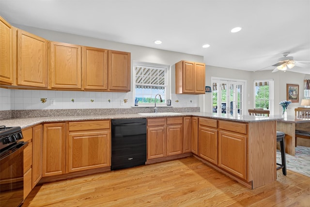 106 Maple Ave, Goshen, NY 10924 - kitchen featuring black appliances, a peninsula, a breakfast bar area, light wood-type flooring, and backsplash