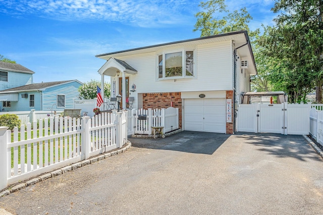 511 N Delaware Ave, Lindenhurst, NY 11757 - split foyer home with a gate, asphalt driveway, brick siding, an attached garage, and a fenced front yard