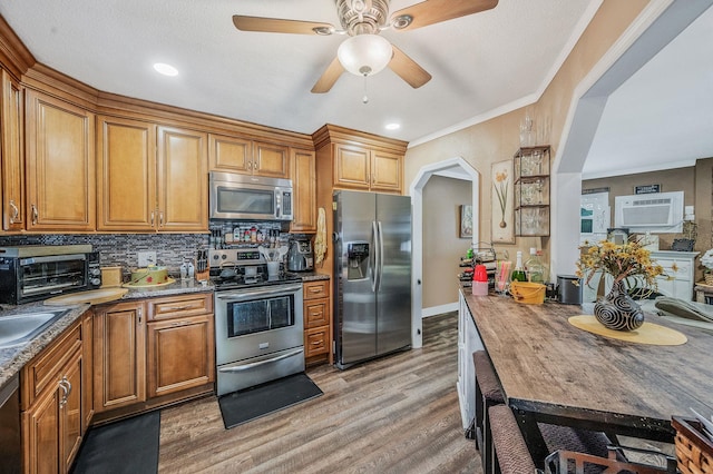511 N Delaware Ave, Lindenhurst, NY 11757 - kitchen featuring appliances with stainless steel finishes, light wood-style floors, brown cabinets, ceiling fan, and ornamental molding