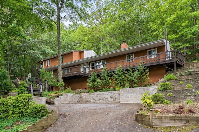 485 Harbor Rd, Cold Spring Harbor, NY 11724 - view of front facade with a chimney, a deck, stairway, and a forest view