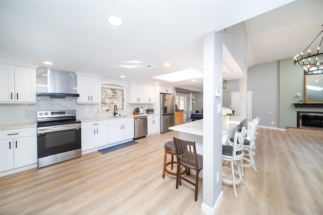 485 Harbor Rd, Cold Spring Harbor, NY 11724 - kitchen with stainless steel appliances, wall chimney range hood, light wood-type flooring, white cabinets, and recessed lighting