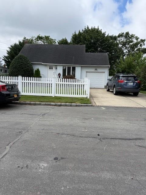 391 31st St, Lindenhurst, NY 11757 - view of front of home featuring driveway, a fenced front yard, and a garage
