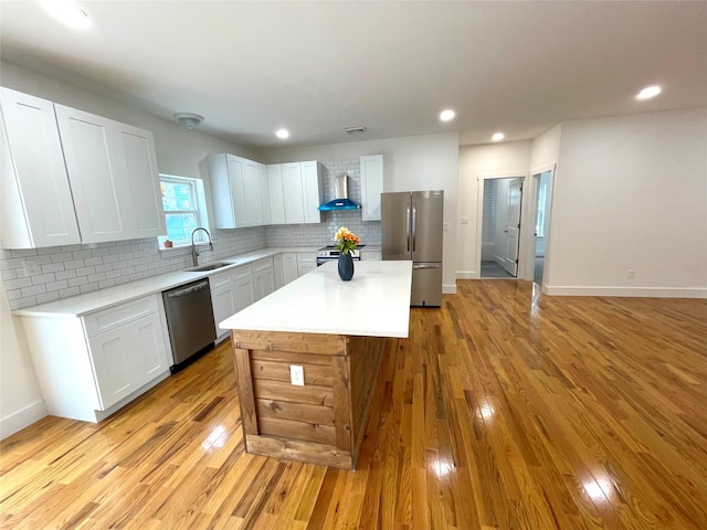 109 Krystyna Rd, White Lake, NY 12787 - kitchen featuring appliances with stainless steel finishes, wall chimney exhaust hood, light wood-type flooring, light countertops, and a kitchen island