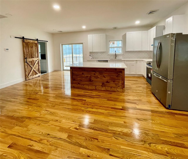 109 Krystyna Rd, White Lake, NY 12787 - kitchen with stainless steel appliances, a barn door, a kitchen island, light wood finished floors, and light countertops