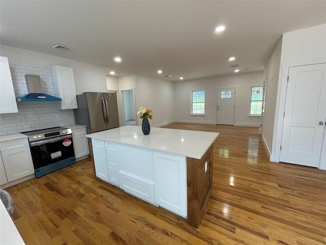 109 Krystyna Rd, White Lake, NY 12787 - kitchen featuring wall chimney exhaust hood, stainless steel appliances, wood finished floors, white cabinets, and a kitchen island
