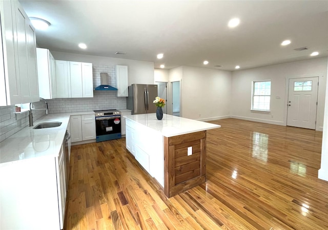 109 Krystyna Rd, White Lake, NY 12787 - kitchen featuring stainless steel appliances, wall chimney range hood, light wood-style floors, backsplash, and a center island
