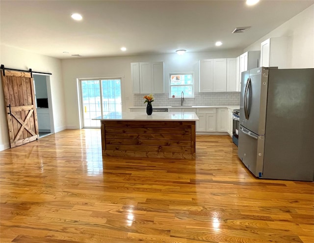 109 Krystyna Rd, White Lake, NY 12787 - kitchen with appliances with stainless steel finishes, a barn door, light wood-style flooring, tasteful backsplash, and light countertops