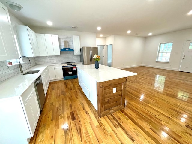 109 Krystyna Rd, White Lake, NY 12787 - kitchen featuring stainless steel appliances, wall chimney exhaust hood, light wood finished floors, tasteful backsplash, and a center island