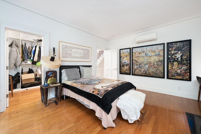 17E 128th St, New York Manhattan, NY 10035 - bedroom with a wall mounted AC, crown molding, light wood-style floors, and a walk in closet