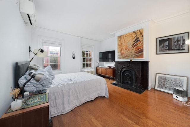 17E 128th St, New York Manhattan, NY 10035 - bedroom featuring a wall mounted air conditioner, radiator, crown molding, wood finished floors, and a fireplace with flush hearth