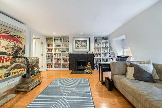 17E 128th St, New York Manhattan, NY 10035 - living area featuring a wall mounted air conditioner, a fireplace with flush hearth, built in shelves, recessed lighting, and wood finished floors