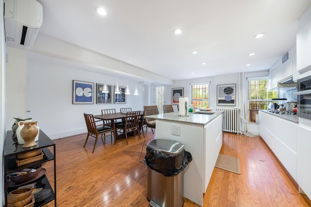 17E 128th St, New York Manhattan, NY 10035 - kitchen featuring an AC wall unit, radiator heating unit, white cabinets, light wood-type flooring, and recessed lighting
