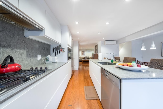 17E 128th St, New York Manhattan, NY 10035 - kitchen featuring stainless steel appliances, under cabinet range hood, a wall unit AC, modern cabinets, and white cabinets