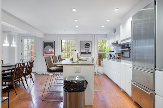 17E 128th St, New York Manhattan, NY 10035 - kitchen with appliances with stainless steel finishes, a center island, modern cabinets, white cabinets, and recessed lighting