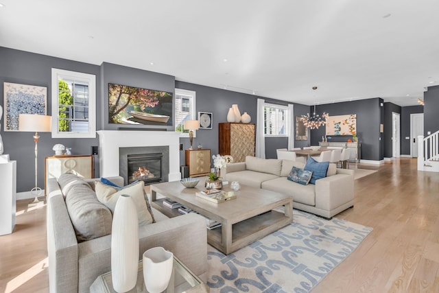 7 Honeysuckle Ln, Rye Brook, NY 10573 - living room featuring wood finished floors, a glass covered fireplace, a chandelier, and stairway