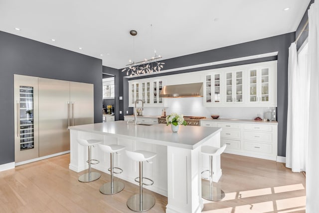 7 Honeysuckle Ln, Rye Brook, NY 10573 - kitchen featuring built in refrigerator, light wood-style floors, light countertops, wall chimney exhaust hood, and white cabinets