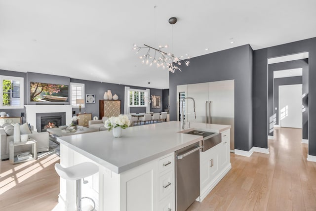 7 Honeysuckle Ln, Rye Brook, NY 10573 - kitchen with a kitchen island with sink, white cabinetry, dishwasher, light wood-type flooring, and recessed lighting