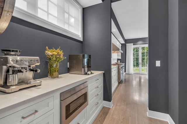 7 Honeysuckle Ln, Rye Brook, NY 10573 - kitchen with white cabinetry, light wood-type flooring, stainless steel appliances, light countertops, and ventilation hood